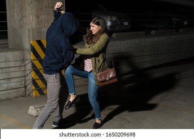 Young Hispanic woman defending herself from attacking thief in alley