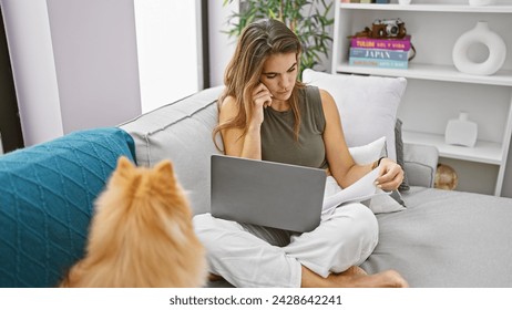 Young hispanic woman with dog sitting on sofa working at home - Powered by Shutterstock