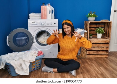 Young Hispanic Woman Doing Laundry Smiling Funny Doing Claw Gesture As Cat, Aggressive And Sexy Expression 