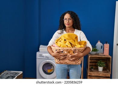 Young Hispanic Woman Doing Laundry Holding Wicker Basket Skeptic And Nervous, Frowning Upset Because Of Problem. Negative Person. 