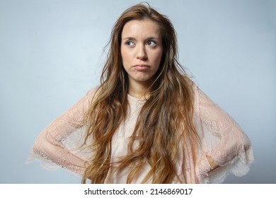 Young Hispanic Woman With Doubt Expression Looking At Side With Hands On Hips Isolated On Grey Background. Human Emotions Concept.