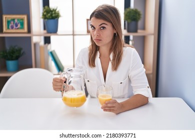 Young Hispanic Woman Drinking Glass Of Orange Juice Skeptic And Nervous, Frowning Upset Because Of Problem. Negative Person. 