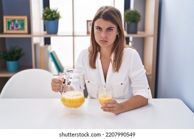 Young Hispanic Woman Drinking Glass Of Orange Juice Skeptic And Nervous, Frowning Upset Because Of Problem. Negative Person. 