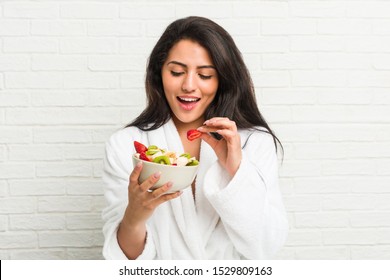 Young Hispanic Woman Eating A Fruit Bowl On The Bed