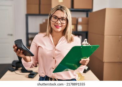 Young Hispanic Woman Ecommerce Business Worker Holding Calculator And Clipboard At Office