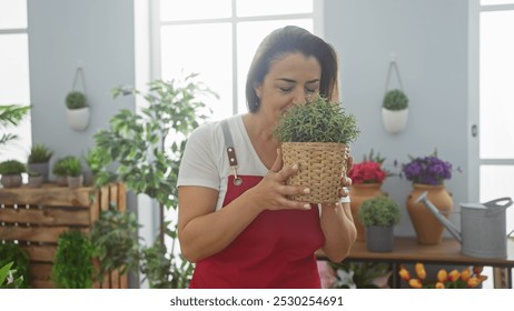 A young hispanic woman enjoys the fragrance of a potted plant in her sunlit home's living room. - Powered by Shutterstock