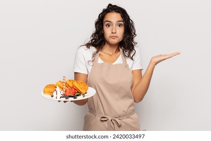 young hispanic woman feeling puzzled and confused, doubting, weighting or choosing different options with funny expression - Powered by Shutterstock