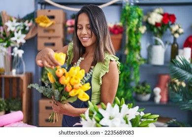 Young hispanic woman florist holding bouquet of flowers at florist store - Powered by Shutterstock