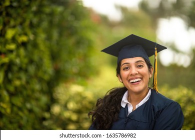 Young Hispanic Woman In Her Graduation Cap And Gown.