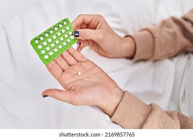 Young hispanic woman holding birth control pills at bedroom - Shutterstock ID 2169857765