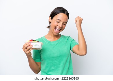 Young Hispanic Woman Holding A Bowl Of Fruit Isolated On White Background Celebrating A Victory