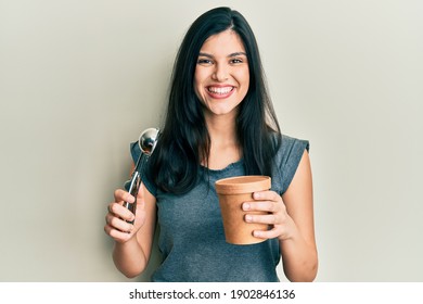 Young hispanic woman holding ice cream smiling with a happy and cool smile on face. showing teeth. 