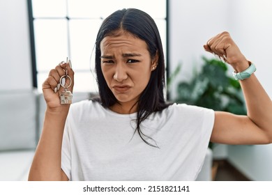 Young Hispanic Woman Holding Keys Of New Home Strong Person Showing Arm Muscle, Confident And Proud Of Power 