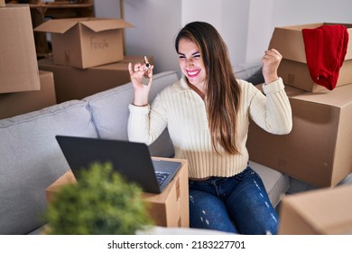 Young Hispanic Woman Holding Keys Of New Home Doing Video Call Screaming Proud, Celebrating Victory And Success Very Excited With Raised Arm 