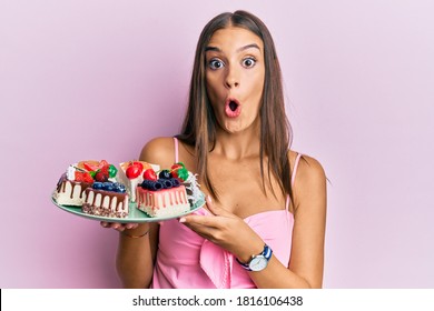 Young Hispanic Woman Holding Plate With Cheesecake Scared And Amazed With Open Mouth For Surprise, Disbelief Face 