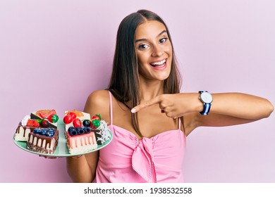 Young Hispanic Woman Holding Plate With Cheesecake Smiling Happy Pointing With Hand And Finger 