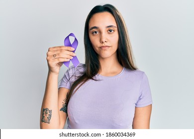 Young hispanic woman holding purple ribbon awareness smiling happy pointing with hand and finger 