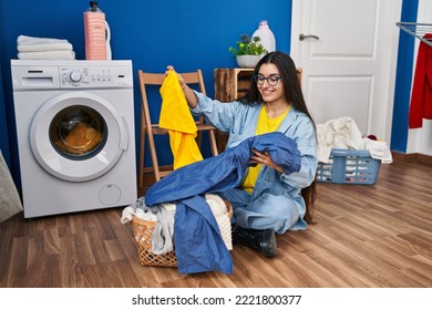 Young Hispanic Woman Holding Towel Washing Clothes At Laundry Room