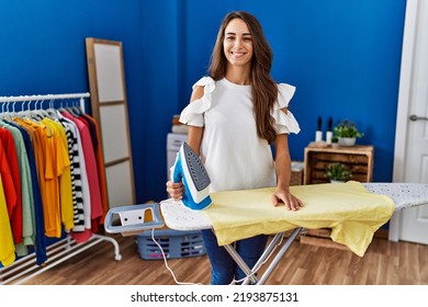 Young hispanic woman ironing clothes at laundry room with a happy and cool smile on face. lucky person.  - Powered by Shutterstock