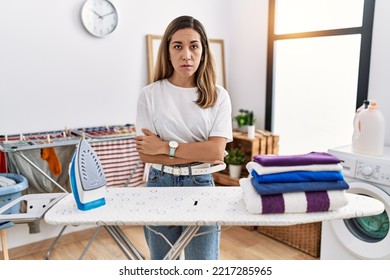 Young Hispanic Woman Ironing Clothes At Laundry Room Relaxed With Serious Expression On Face. Simple And Natural Looking At The Camera. 