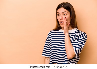 Young hispanic woman isolated on beige background being shocked because of something she has seen.
