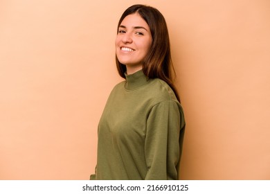 Young Hispanic Woman Isolated On Beige Background Confident Keeping Hands On Hips.