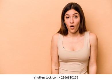Young hispanic woman isolated on beige background being shocked because of something she has seen.