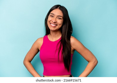 Young Hispanic Woman Isolated On Blue Background Confident Keeping Hands On Hips.