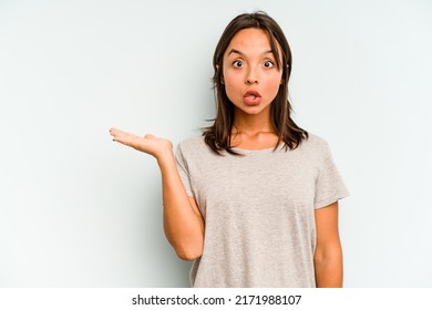 Young hispanic woman isolated on blue background being shocked because of something she has seen.