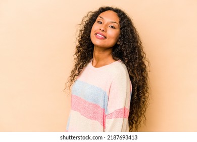 Young Hispanic Woman Isolated On Beige Background Confident Keeping Hands On Hips.