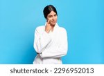 young hispanic woman keeping an eye on you, not trusting, watching and staying alert and vigilant. bathrobe concept