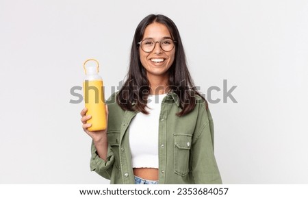 young hispanic woman looking happy and pleasantly surprised and holding a coffee thermos