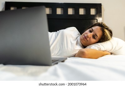 Young Hispanic Woman Lying In Bed Watching Her Favorite Series On Her Laptop