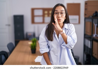 Young Hispanic Woman At The Office Hand On Mouth Telling Secret Rumor, Whispering Malicious Talk Conversation 