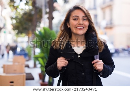 Young hispanic woman on blurred city street