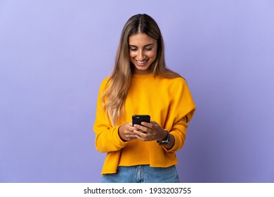 Young Hispanic Woman Over Isolated Purple Background Sending A Message With The Mobile