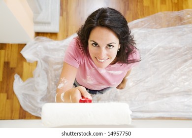 Young Hispanic Woman Painting Wall Of New Home, High Angle View