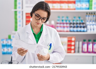 Young Hispanic Woman Pharmacist Holding Prescription And Pills Bottle At Pharmacy