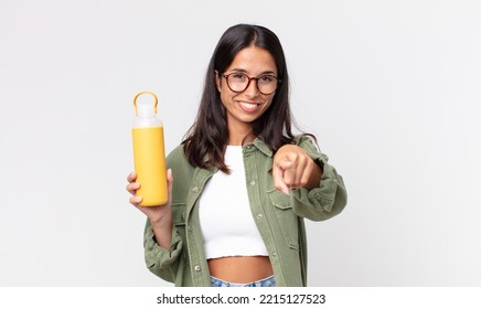 Young Hispanic Woman Pointing At Camera Choosing You And Holding A Coffee Thermos