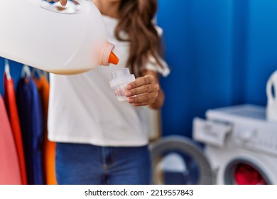 Young Hispanic Woman Pouring Detergent At Laundry Room