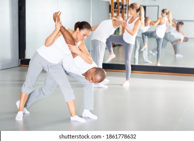Young hispanic woman practicing basic protection skills with man during self defense course in gym - Shutterstock ID 1861778632