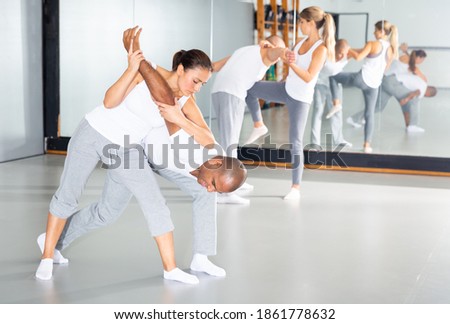 Young hispanic woman practicing basic protection skills with man during self defense course in gym