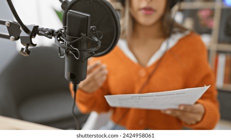 A young hispanic woman rehearses script indoor at a radio studio. - Powered by Shutterstock