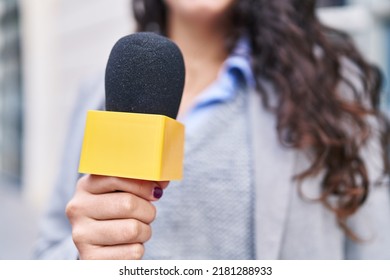 Young Hispanic Woman Reporter Working Using Microphone At Street