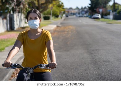 Young hispanic woman riding her bicycle and wearing a face mask against covid-19 - Powered by Shutterstock