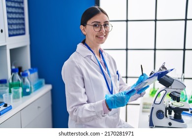 Young Hispanic Woman Scientist Writing On Document At Laboratory