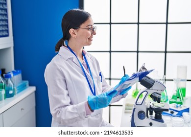 Young Hispanic Woman Scientist Writing On Document At Laboratory