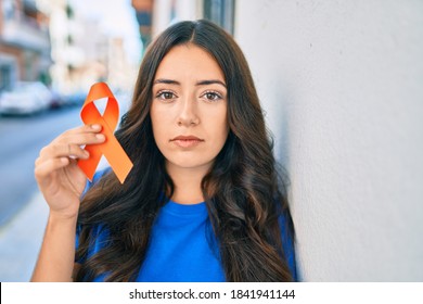 Young hispanic woman with serious expression holding orange ribbon at the city. - Shutterstock ID 1841941144