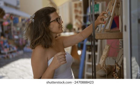 A young hispanic woman shops for jewelry on the charming streets of gallipoli, puglia, italy, wearing a white strapless dress and glasses. - Powered by Shutterstock