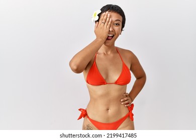 Young Hispanic Woman With Short Hair Wearing Bikini Covering One Eye With Hand, Confident Smile On Face And Surprise Emotion. 